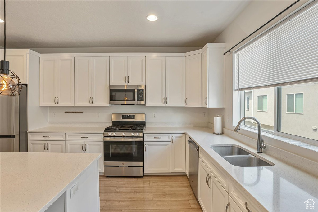 Kitchen featuring appliances with stainless steel finishes, light wood-style flooring, white cabinetry, recessed lighting, and light stone countertops