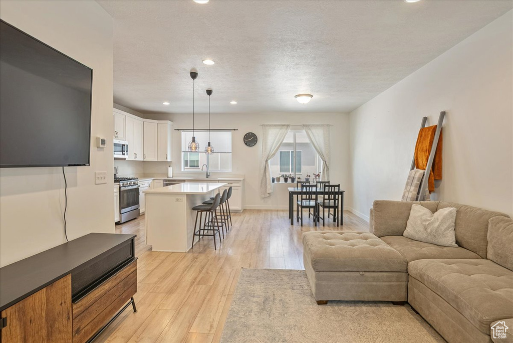 Living area featuring light wood-style flooring, recessed lighting, and a textured ceiling