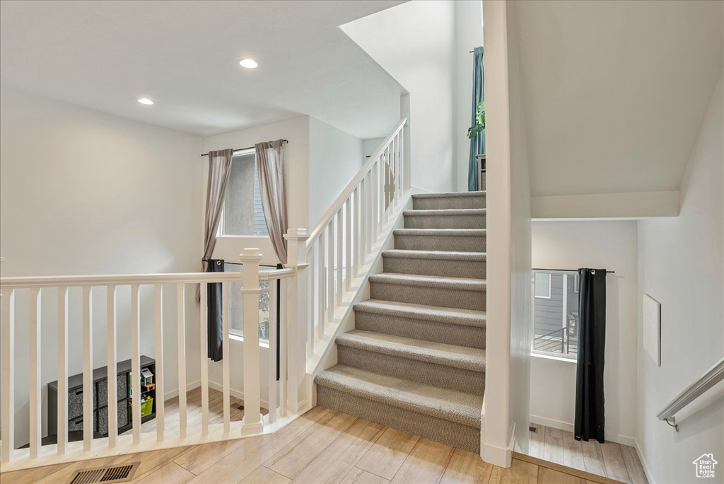 Stairway featuring wood finished floors and recessed lighting