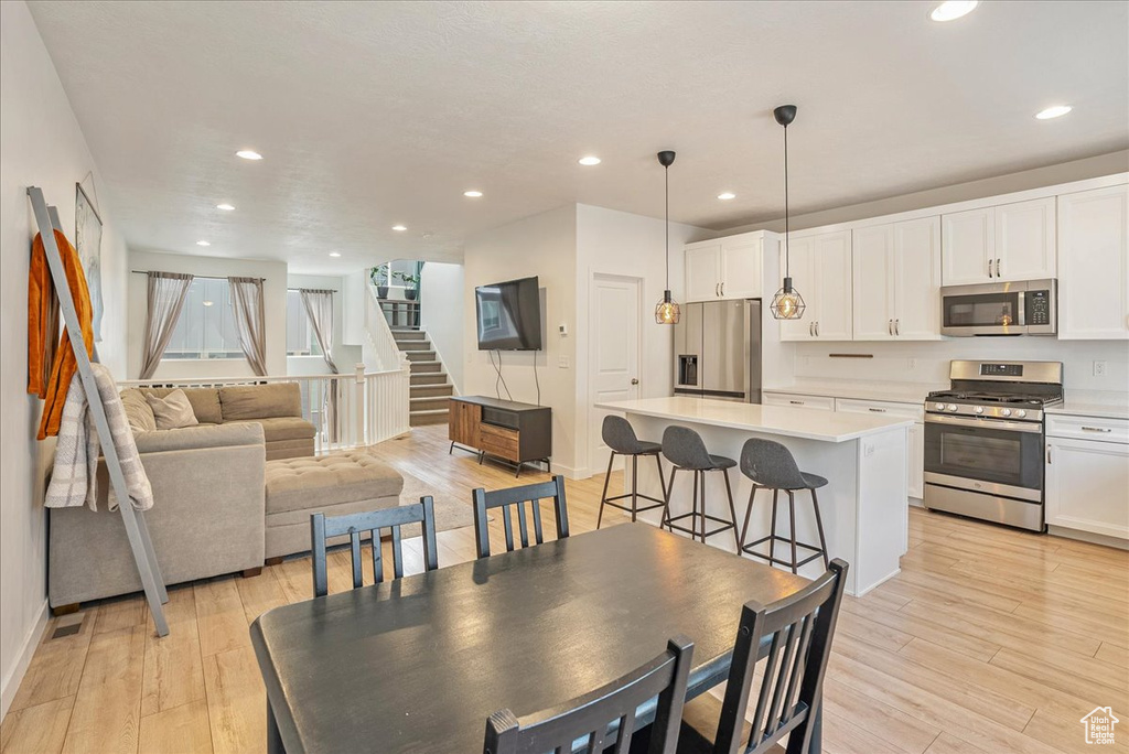 Dining area with recessed lighting, light wood-type flooring, and stairs