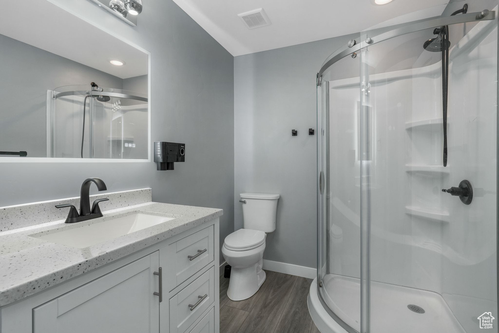 Bathroom with a shower stall, wood finished floors, toilet, vanity, and baseboards