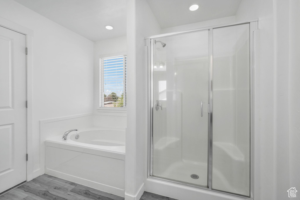 Bathroom featuring a stall shower, a bath, recessed lighting, and wood finished floors