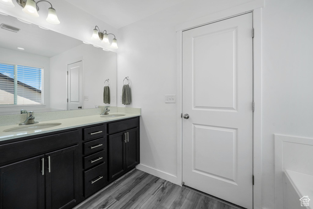 Bathroom with double vanity, wood finished floors, and baseboards