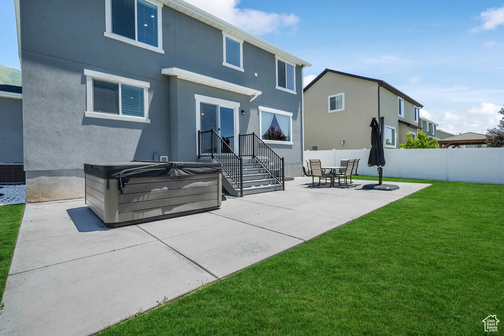 Rear view of house with a patio area, a hot tub, and stucco siding