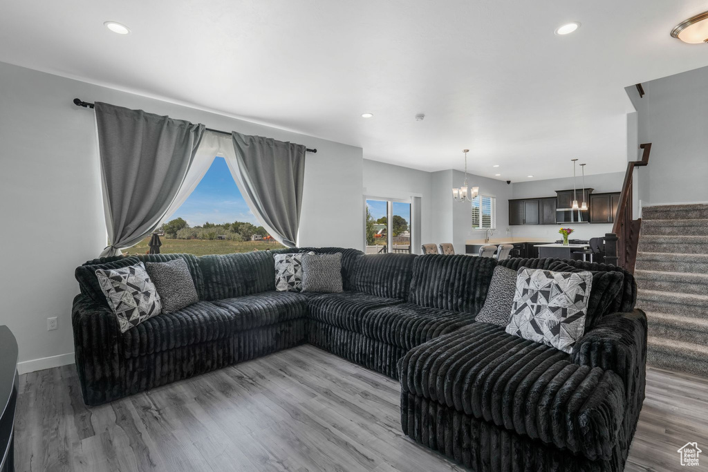 Living area with a chandelier, light wood-style floors, recessed lighting, and stairs