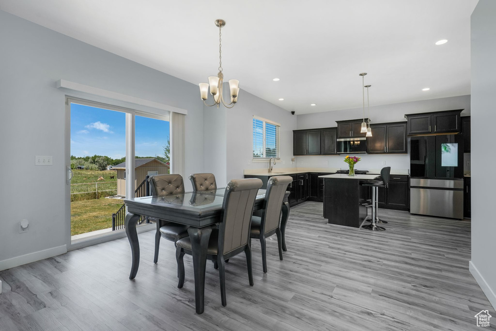 Dining space featuring a chandelier, light wood-style floors, baseboards, and recessed lighting