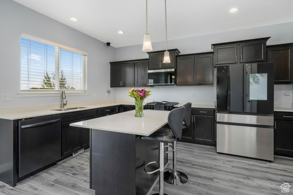 Kitchen with dishwasher, freestanding refrigerator, a sink, a breakfast bar, and light countertops