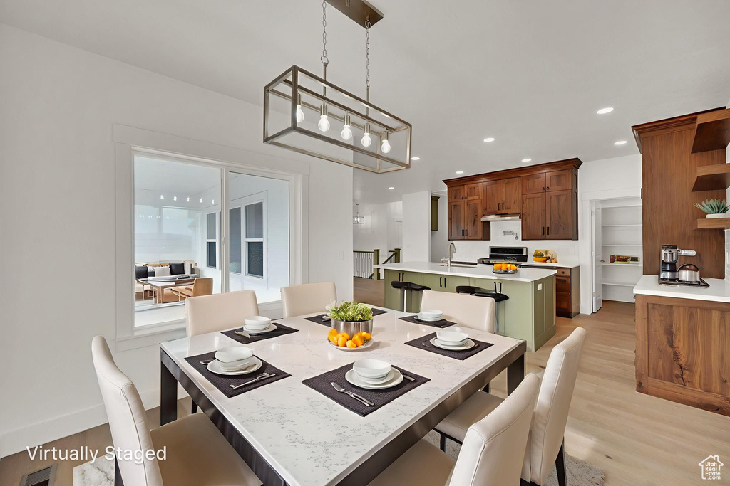 Dining area with light wood finished floors and recessed lighting