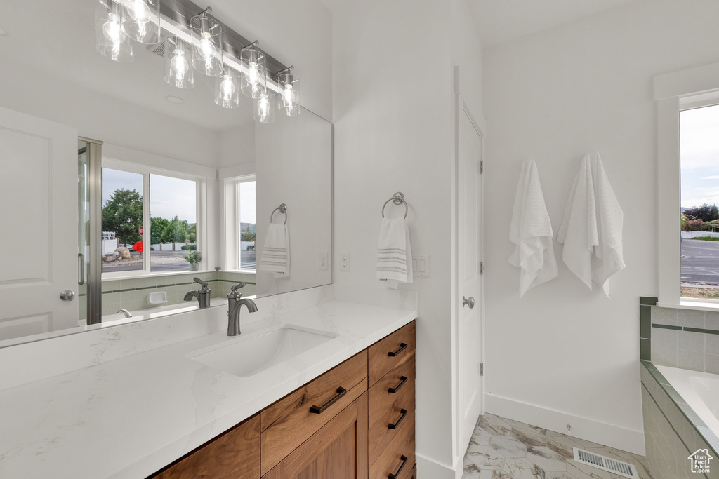 Full bath featuring marble finish floors, vanity, and a tub