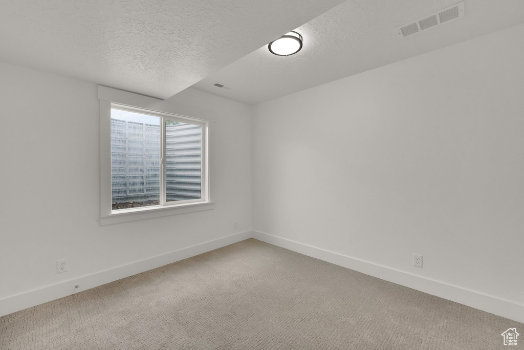 Empty room with a textured ceiling and light carpet