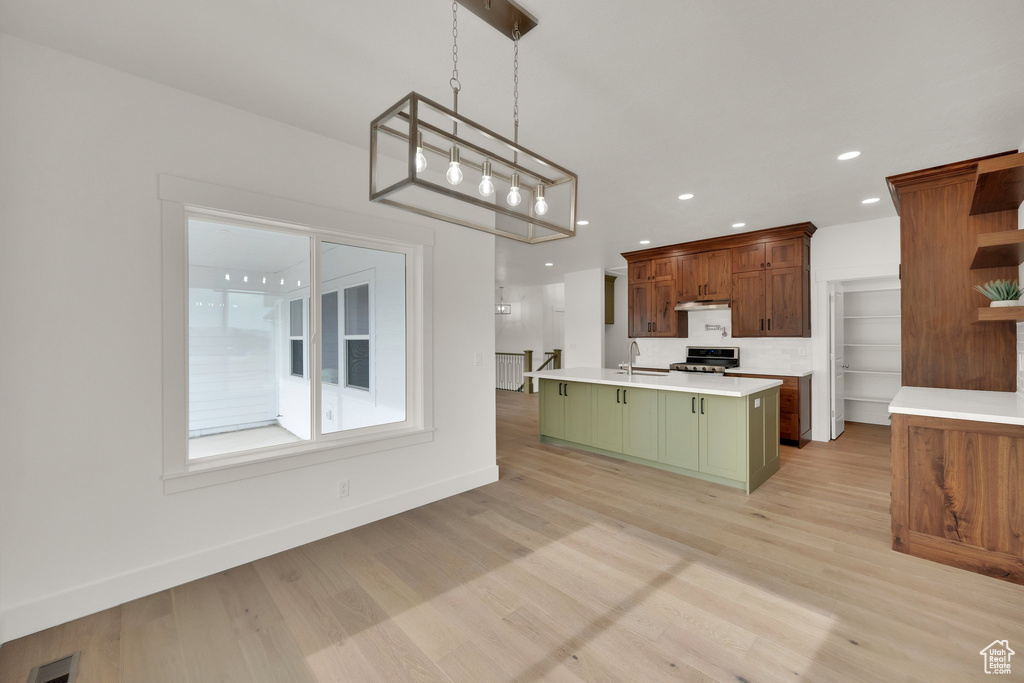 Kitchen with open shelves, light countertops, green cabinets, light wood-style floors, and recessed lighting