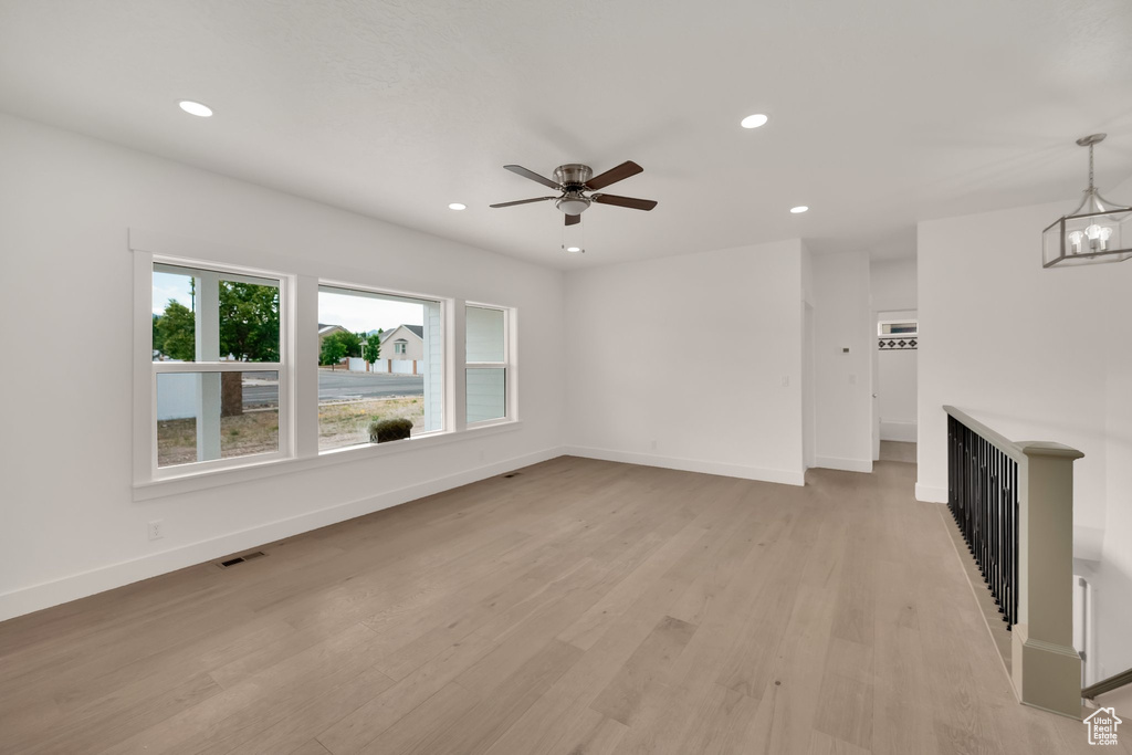 Unfurnished living room with recessed lighting, light wood-type flooring, ceiling fan, and a chandelier