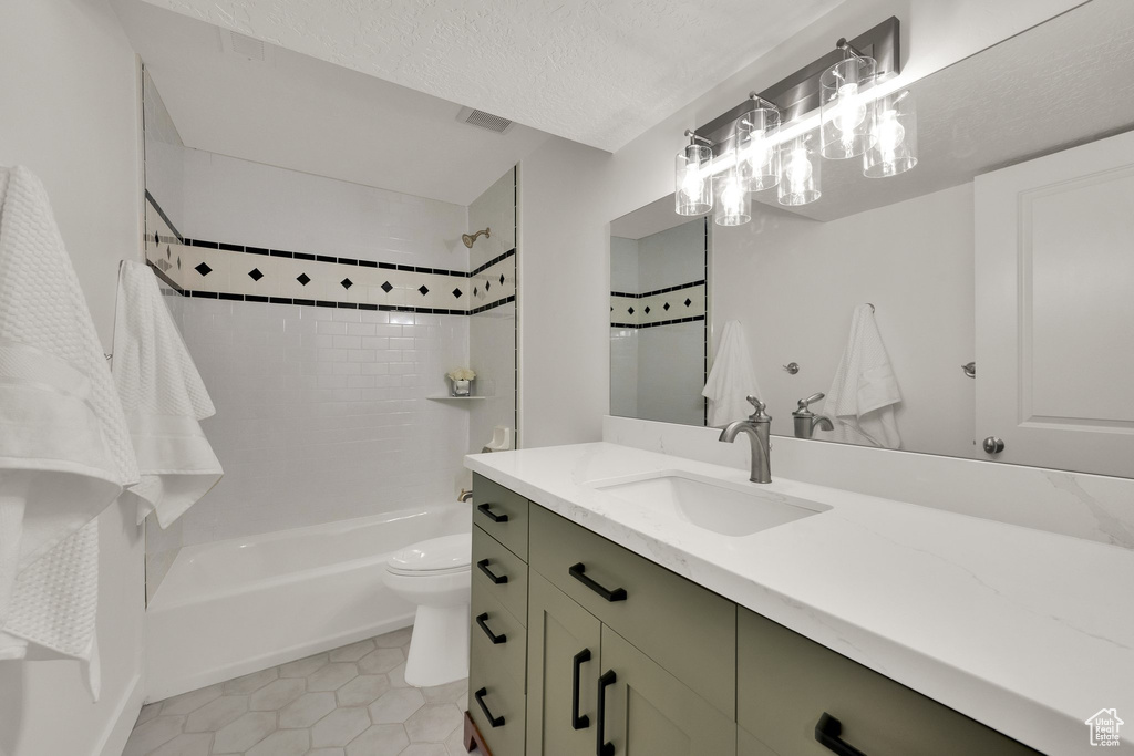 Full bath featuring vanity, tub / shower combination, tile patterned flooring, and a textured ceiling