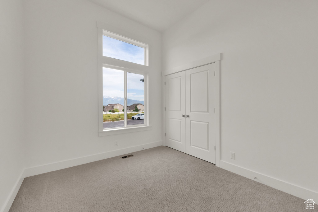 Unfurnished bedroom with light colored carpet and baseboards