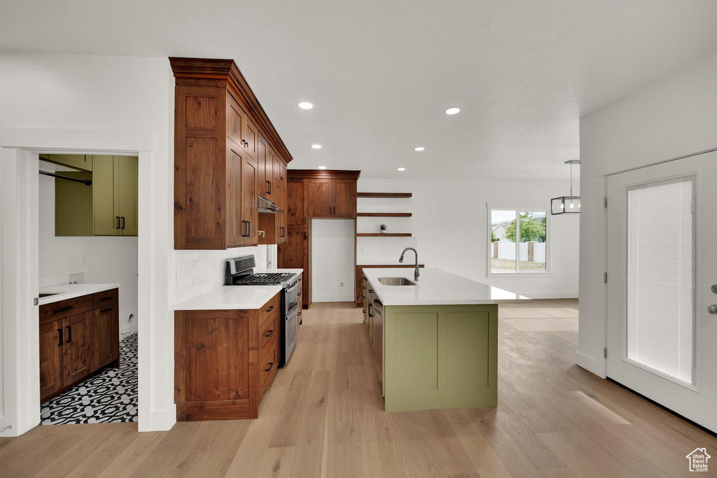 Kitchen with double oven range, under cabinet range hood, light wood-type flooring, recessed lighting, and light countertops