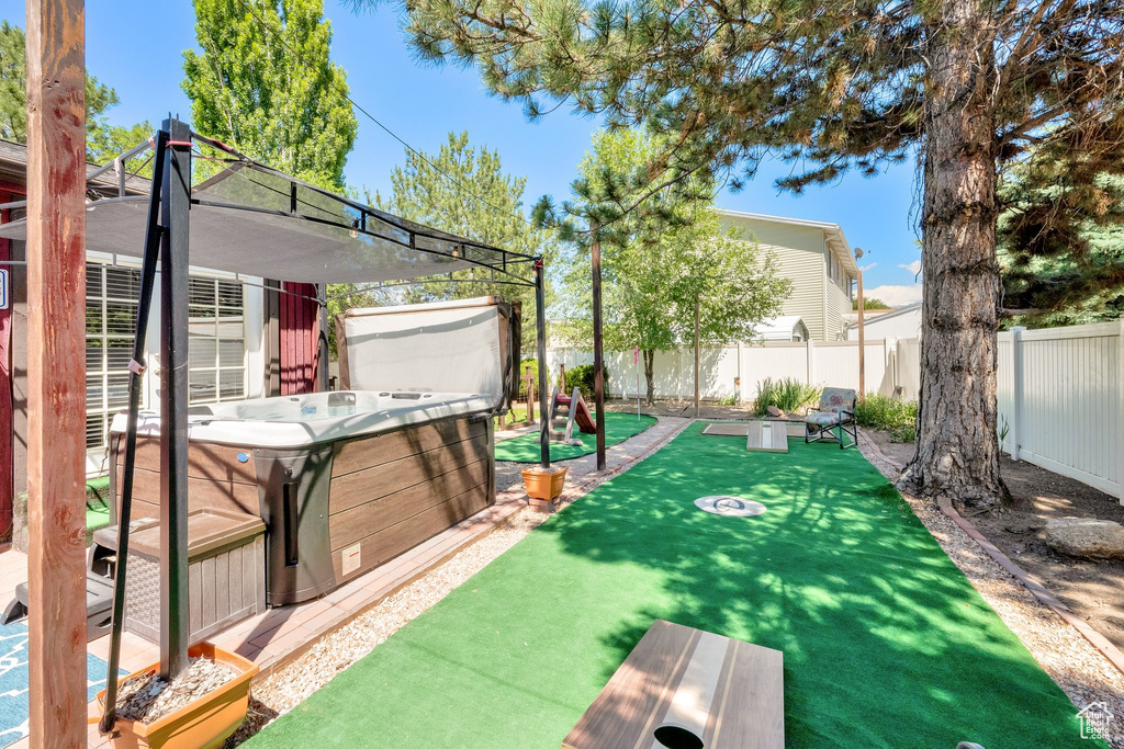 Fenced backyard featuring a hot tub and an area to practice putting