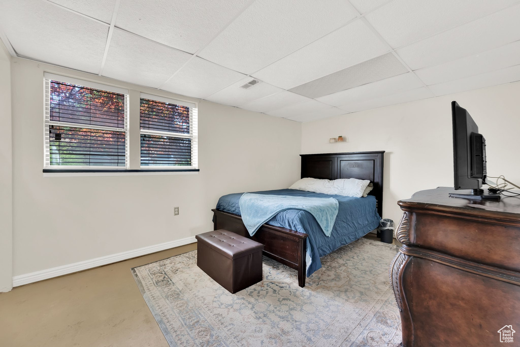 Bedroom featuring a paneled ceiling and finished concrete flooring