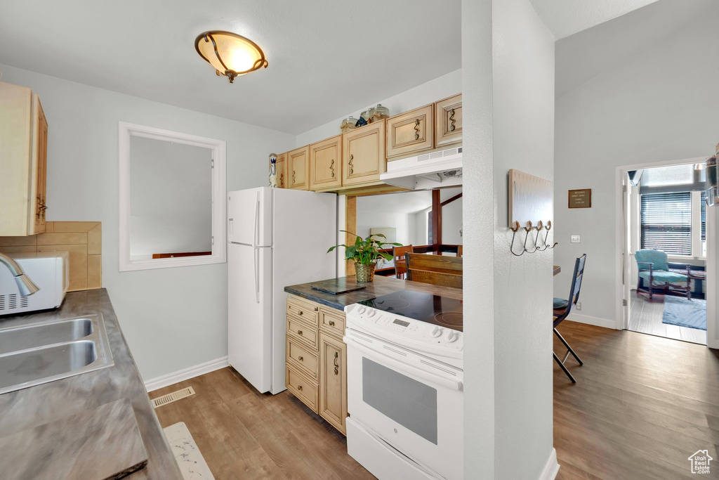 Kitchen with white appliances, under cabinet range hood, light wood-style flooring, and light brown cabinetry