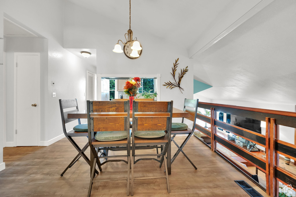 Dining area featuring a chandelier, wood finished floors, and high vaulted ceiling