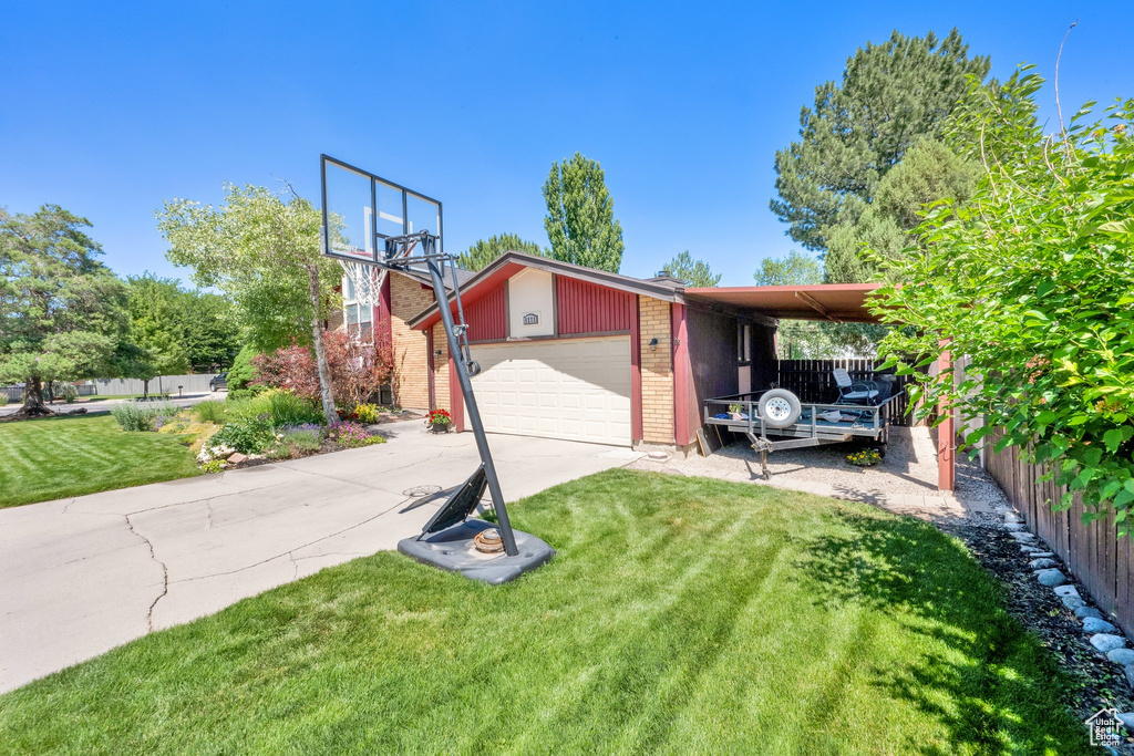 View of front of property featuring brick siding, concrete driveway, an outbuilding, a carport, and an attached garage