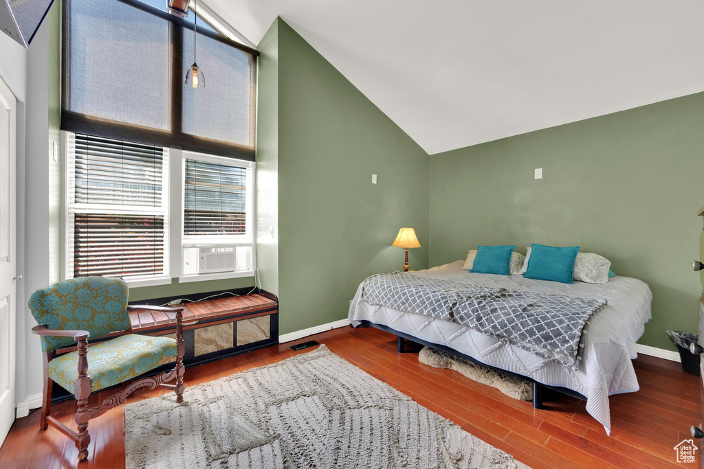 Bedroom with vaulted ceiling, wood finished floors, and cooling unit