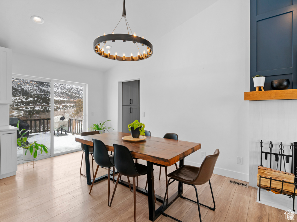 Dining space featuring a chandelier, light wood finished floors, recessed lighting, and vaulted ceiling
