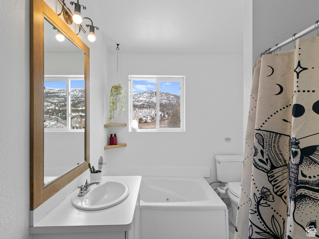 Bathroom featuring a jetted tub, plenty of natural light, vanity, and a mountain view