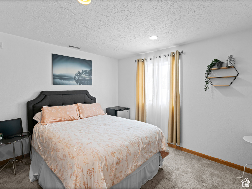 Carpeted bedroom featuring a textured ceiling and baseboards