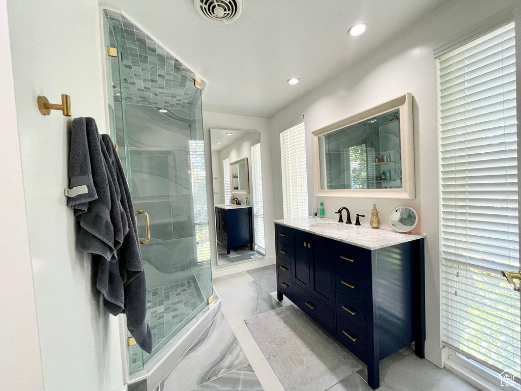 Bathroom with vanity, marble tiled floors, a stall shower, and recessed lighting