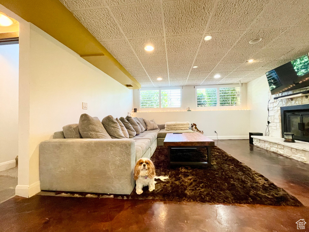 Living area with recessed lighting, a stone fireplace, and concrete flooring