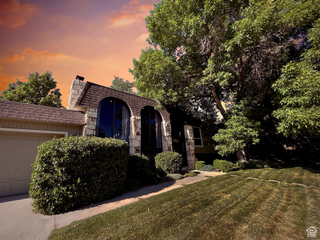 Front facade with an attached garage, a front yard, and mansard roof