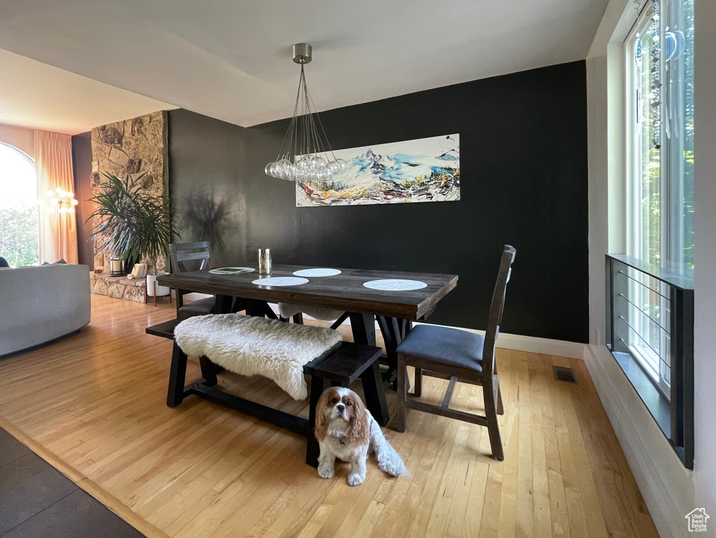 Dining space with light wood-style floors, a chandelier, and an accent wall