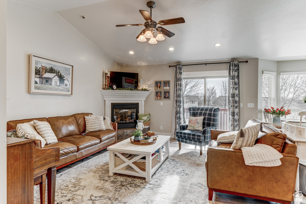 Living room with a ceiling fan, a glass covered fireplace, vaulted ceiling, recessed lighting, and wood finished floors