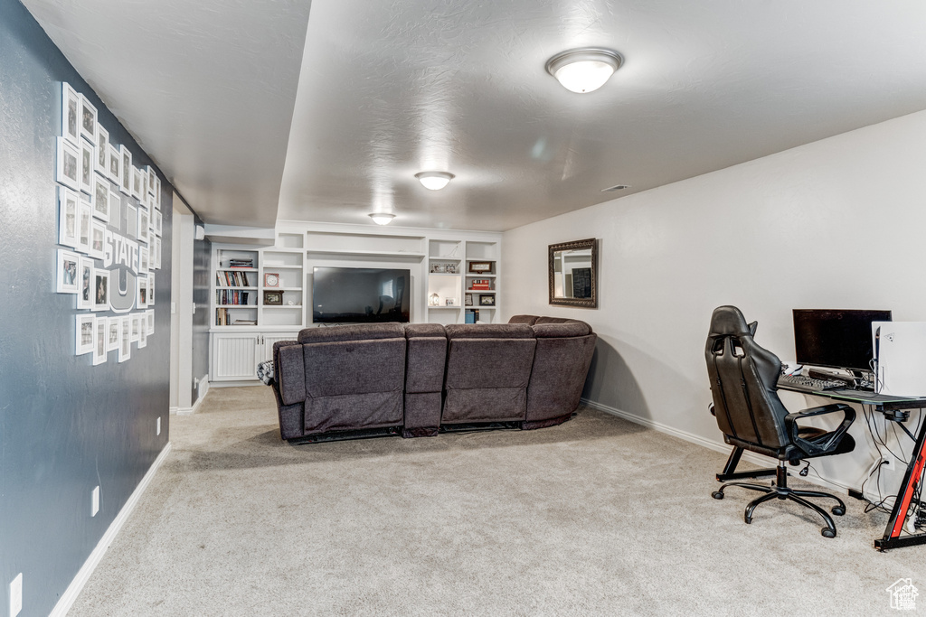 Living room featuring light carpet, built in shelves, and an office area