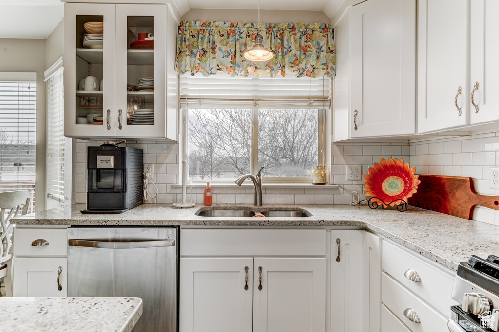 Kitchen with appliances with stainless steel finishes, healthy amount of natural light, white cabinets, and glass insert cabinets