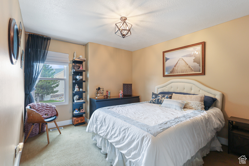 Carpeted bedroom featuring a textured ceiling and baseboards