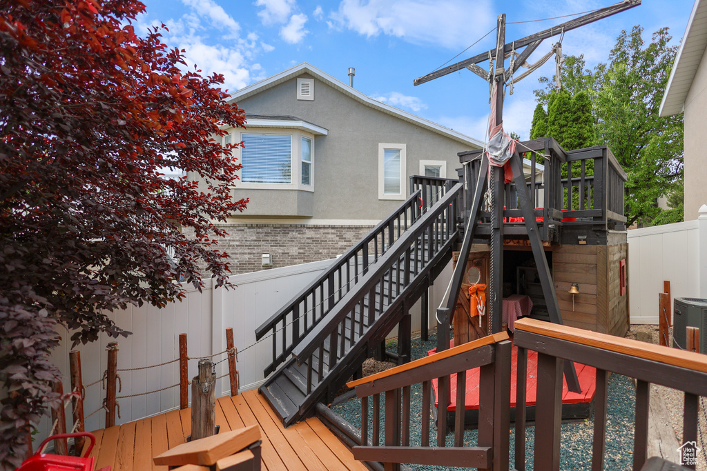 Wooden terrace featuring stairway and central AC unit