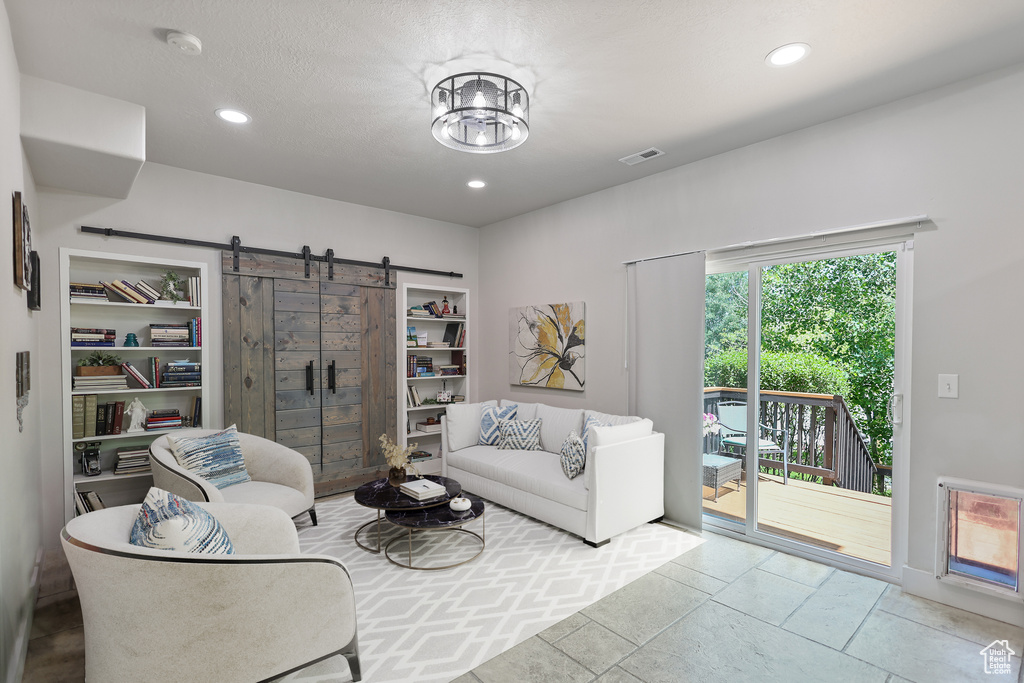 Living room with a barn door, recessed lighting, and tile patterned flooring