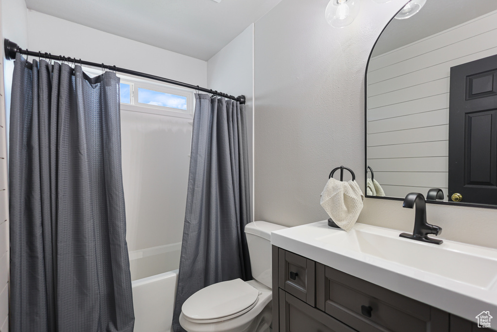 Bathroom with shower / tub combo with curtain, toilet, vanity, and wooden walls