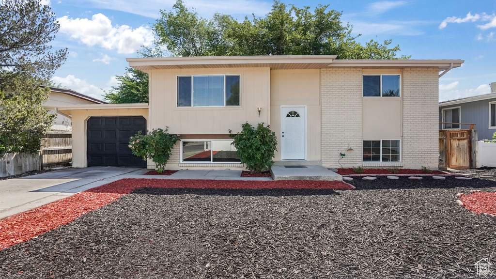 Raised ranch with brick siding, a garage, and concrete driveway