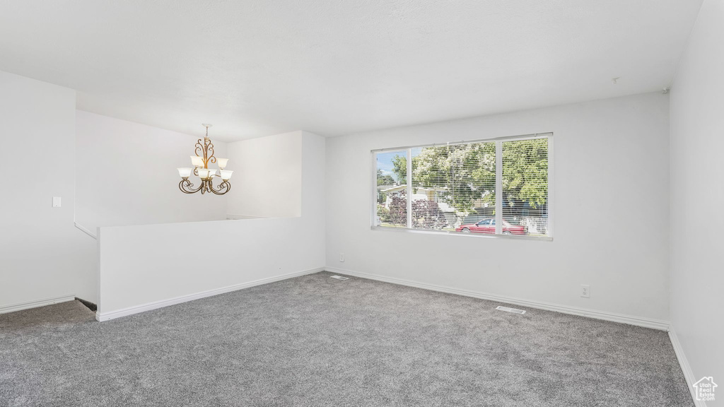 Empty room featuring carpet and a chandelier
