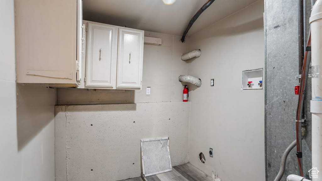 Laundry area featuring cabinet space, hookup for a washing machine, electric dryer hookup, and wood finished floors
