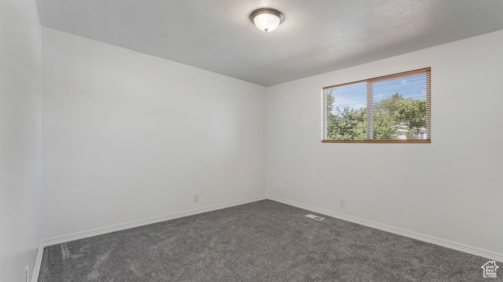 Unfurnished room with dark carpet and baseboards