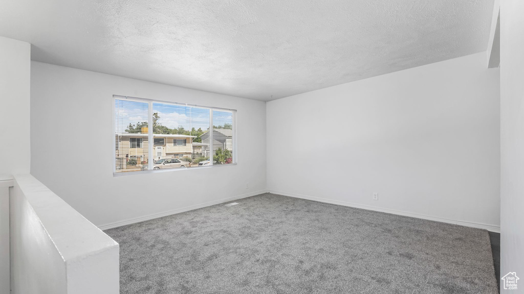 Spare room featuring a textured ceiling and carpet