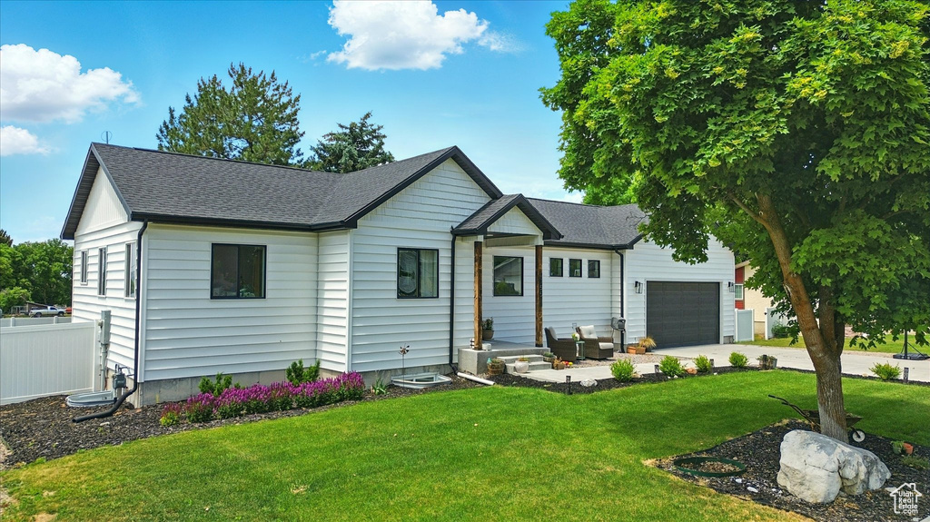 View of front of property with a garage, roof with shingles, and concrete driveway