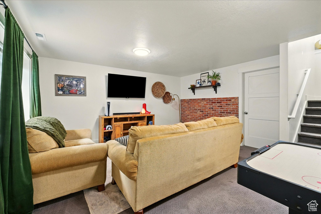 Living area with carpet, stairway, and brick wall