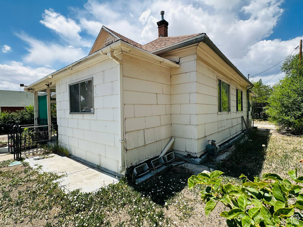 View of side of home featuring a chimney and roof with shingles