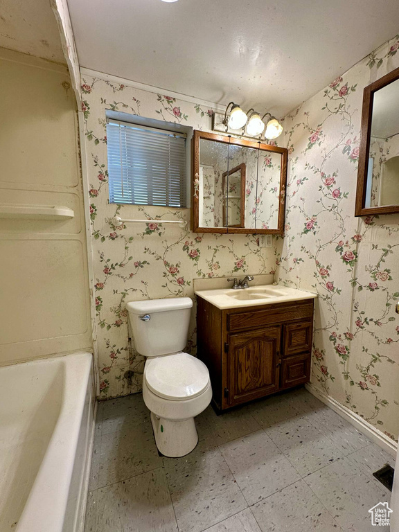 Bathroom featuring a bathtub, wallpapered walls, and vanity