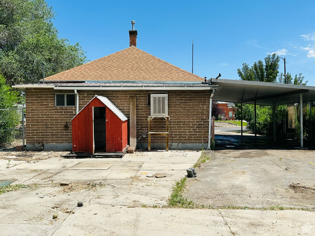 Rear view of house featuring a chimney, brick siding, and a shingled roof