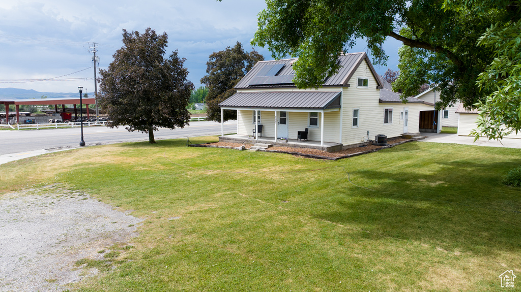 Country-style home featuring covered porch, solar panels, a front yard, a metal roof, and a mountain view
